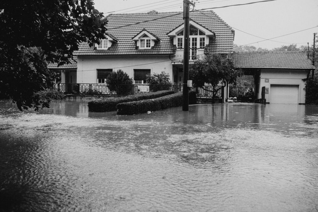 pexels-photo-28447778-28447778 A black and white image showing a suburban house surrounded by floodwater.