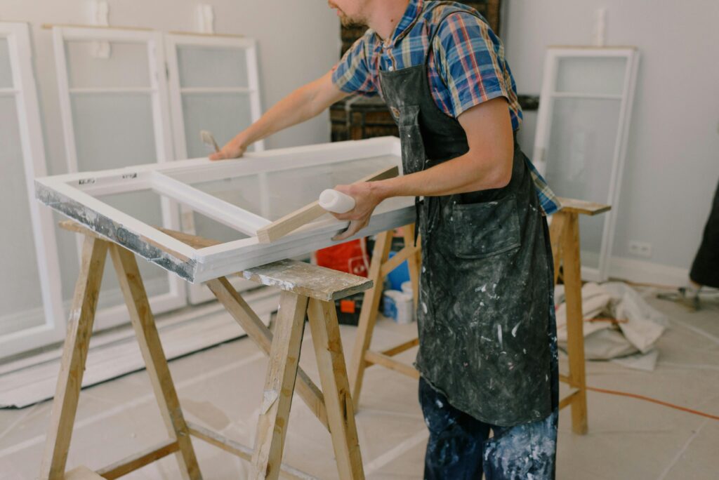 pexels-photo-5691501-5691501 A skilled craftsman repairing a window frame indoors using tools and expertise.