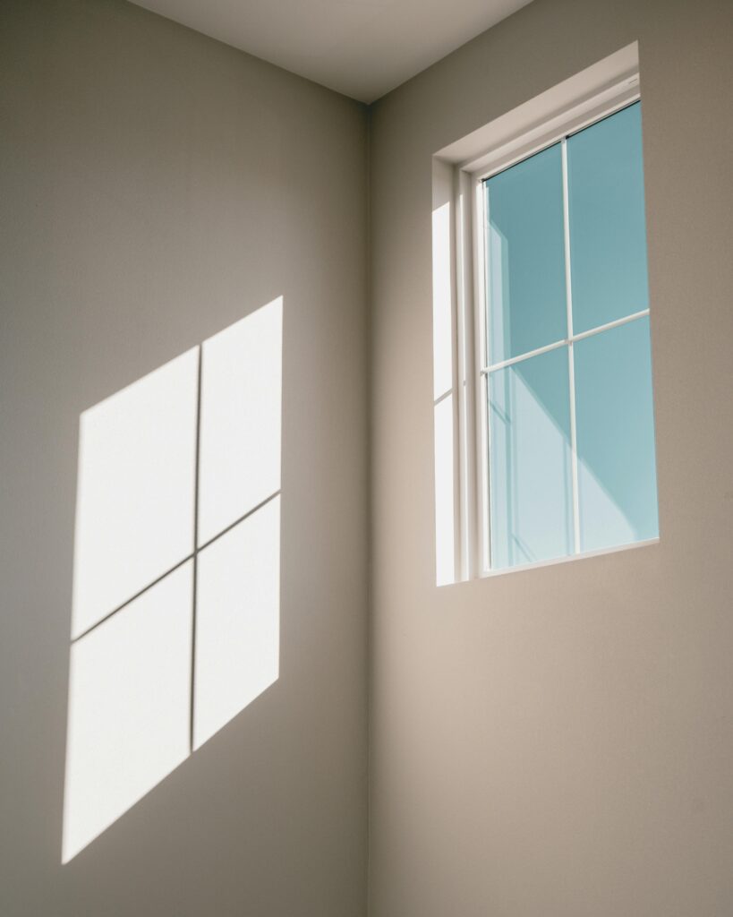 pexels-photo-5872042-5872042 Low angle of window with glazing bars in light simple room with shadow on white wall