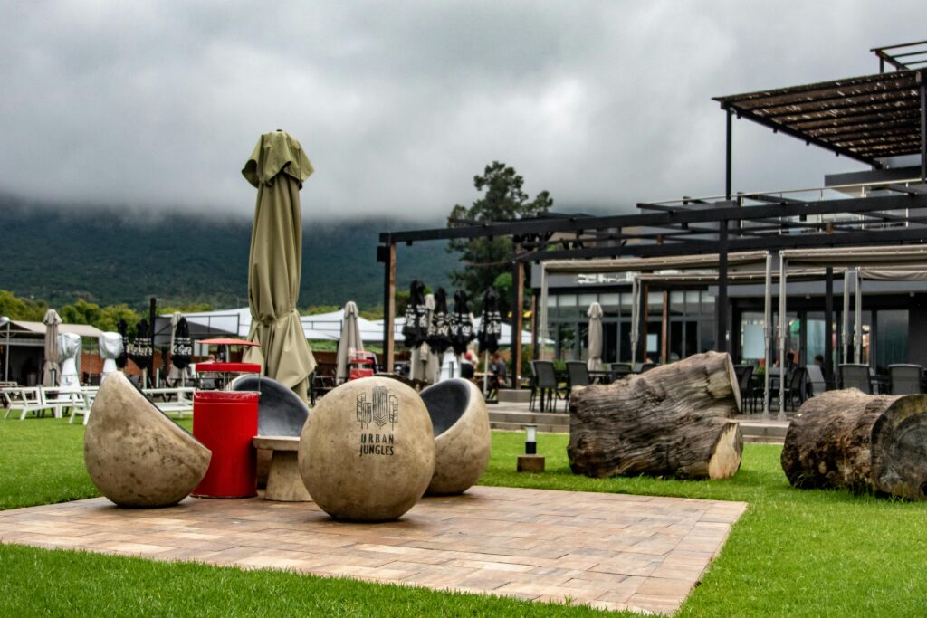pexels-photo-5958761-5958761 Contemporary outdoor seating with stone chairs and rustic logs against a foggy mountain backdrop.
