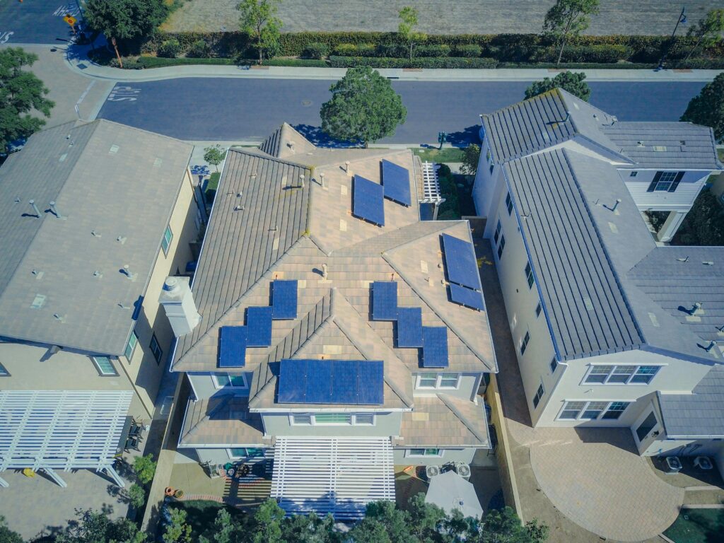 pexels-photo-9875683-9875683 Aerial view of suburban homes equipped with solar panels in a sunny neighborhood.