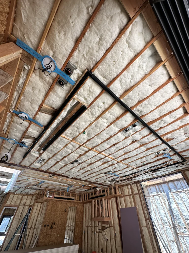 Wide interior ceiling insulation with lighting rough-ins and structural framing during Southern California custom home construction