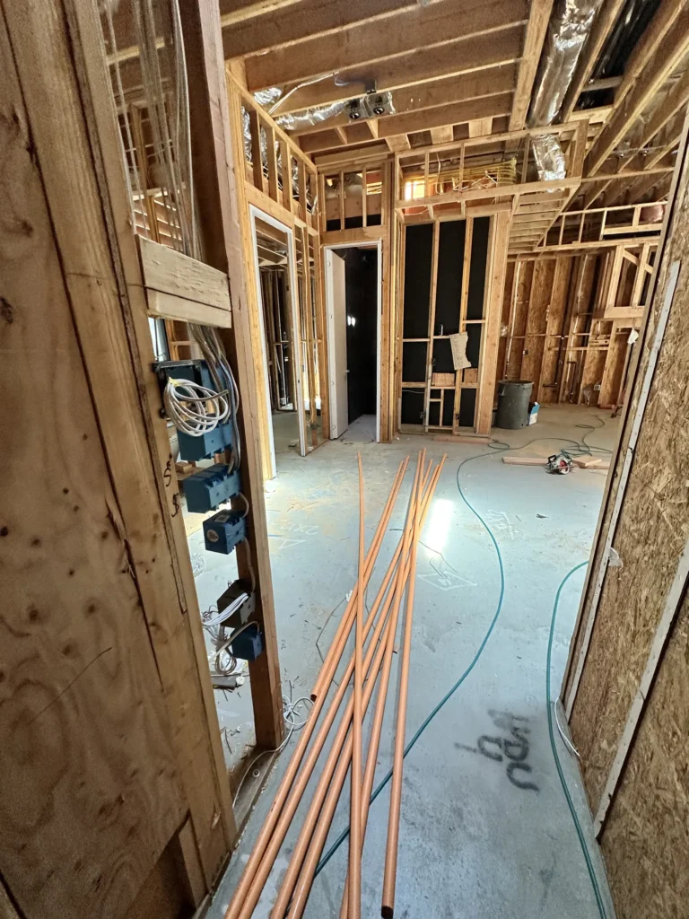 Interior framing and utility rough-in corridor during Southern California custom home construction