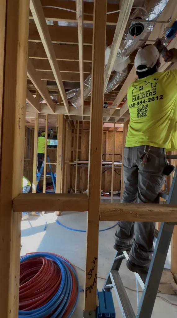 Worker installing ductwork within the framed ceiling.