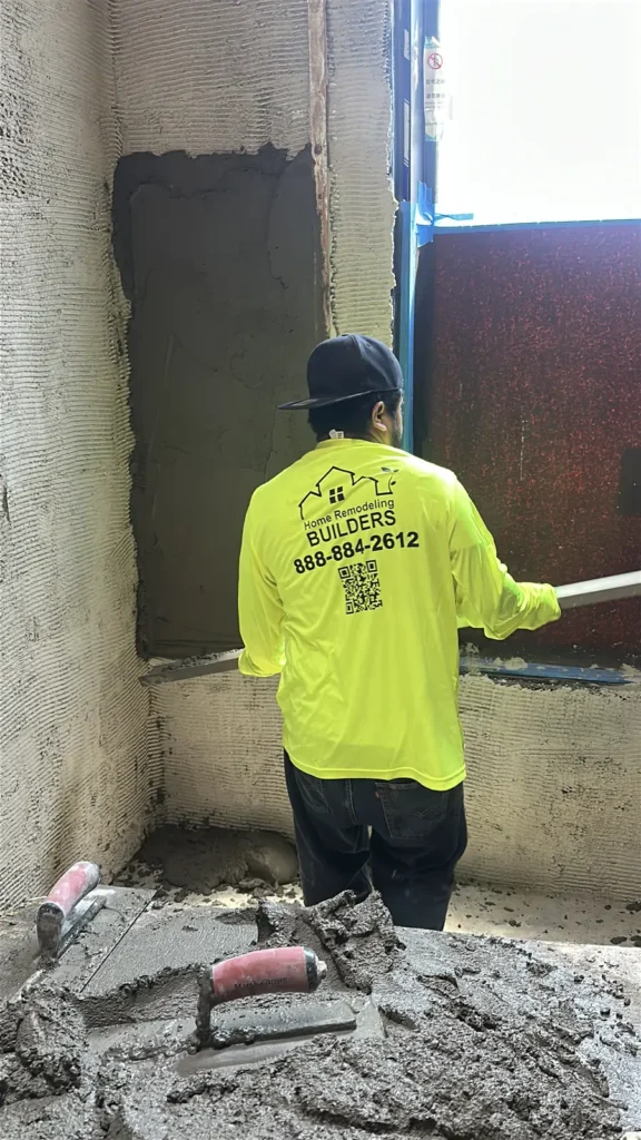 Worker preparing a wall beneath a bathroom window.
