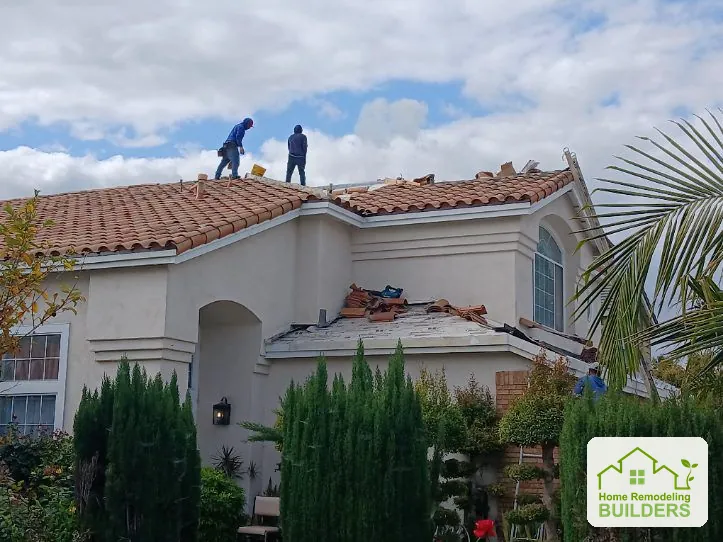 Roofers working along the upper tile roof. Cerritos roofing project.