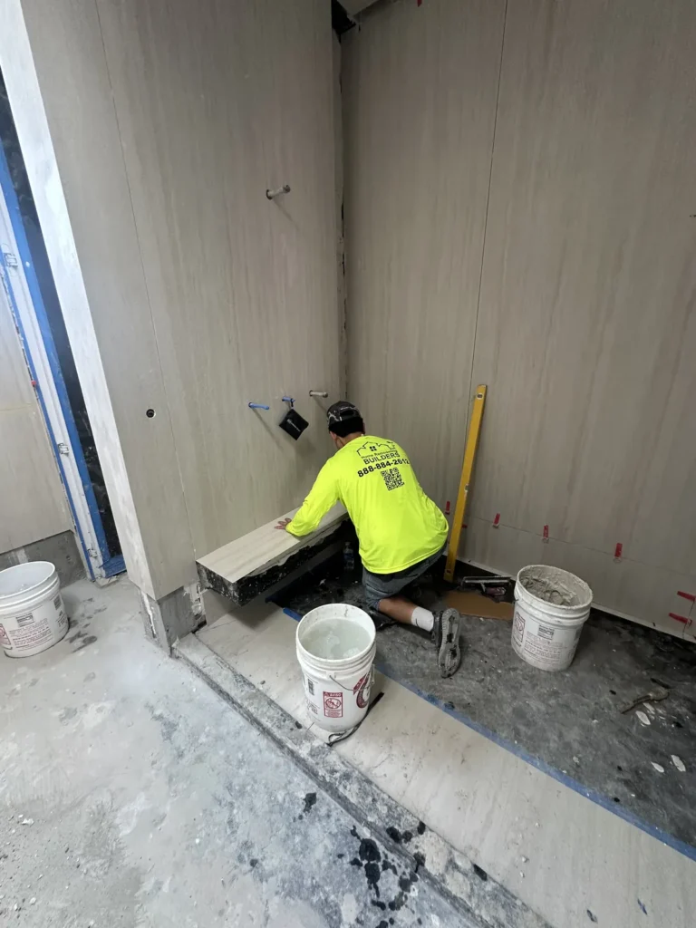 Large wall tiles being fitted in the bathroom corner.