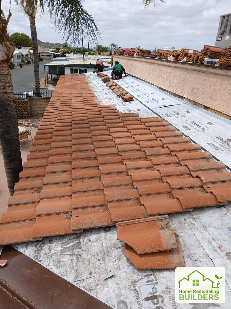 A roofer installs tiles along a long roof slope. Hemet roofing project.
