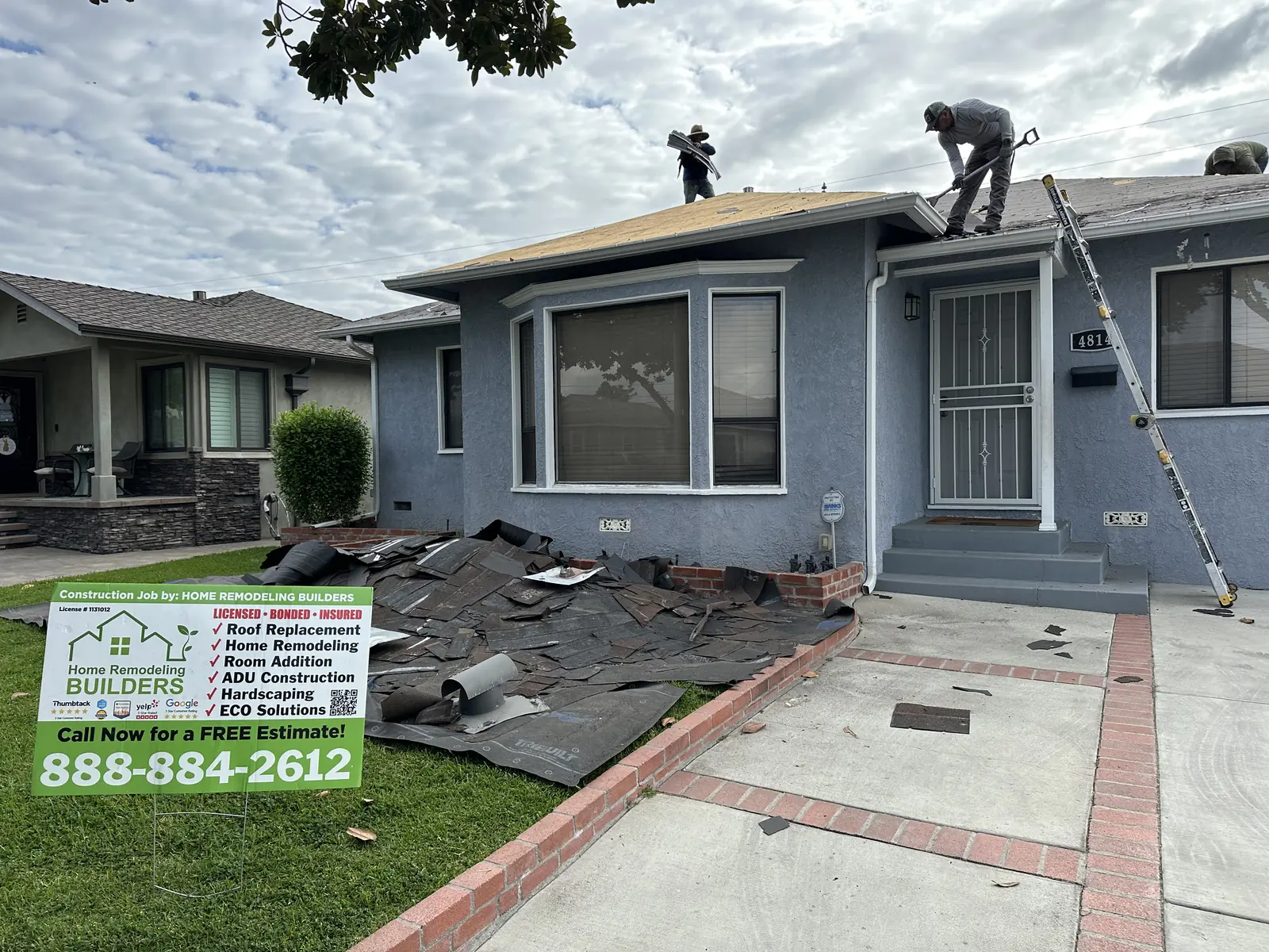 The roofing crew at work behind the company jobsite sign. Lakewood roofing project.