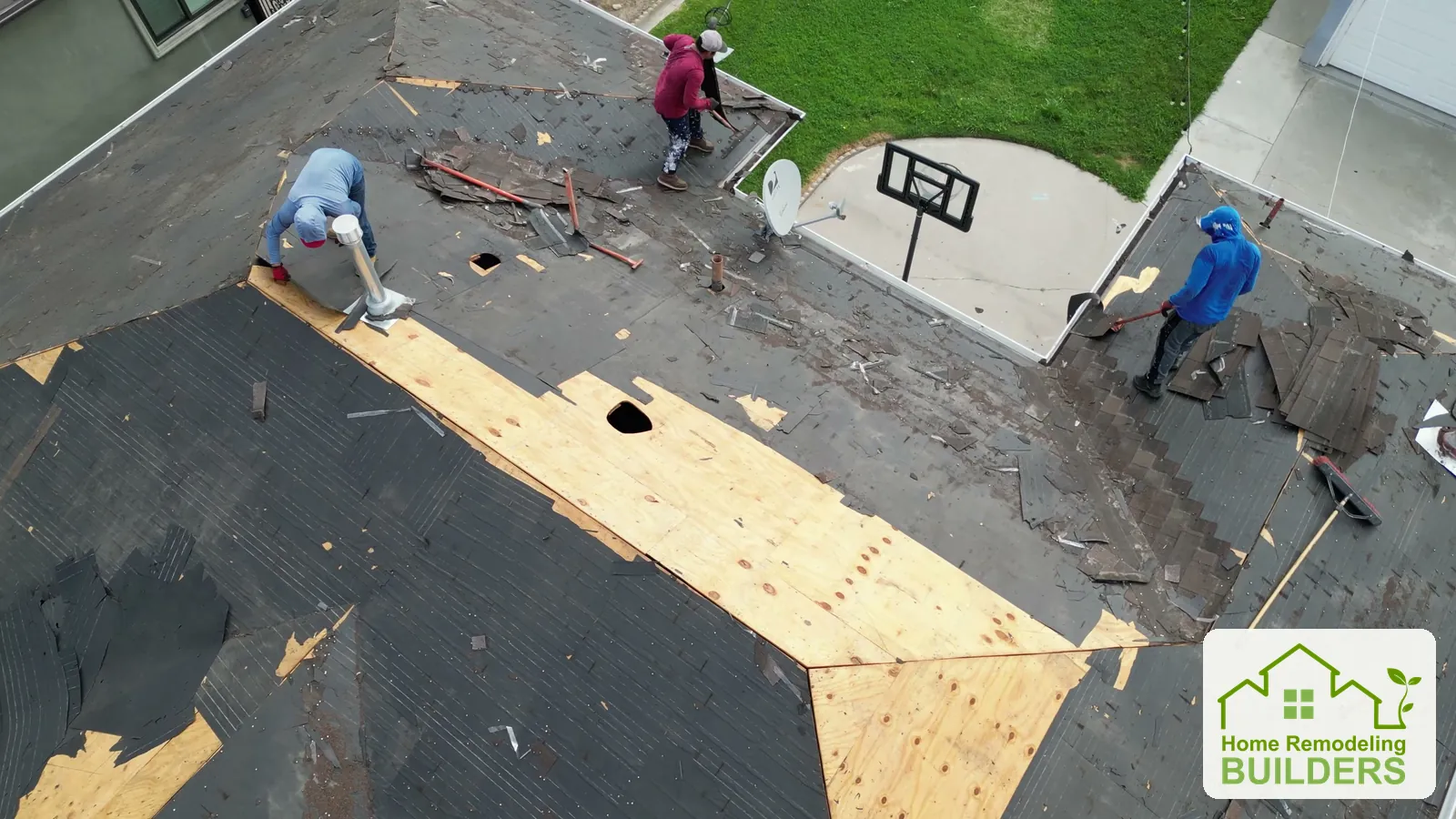 Crew members clear the opposite roof slope and expose the underlying deck. Lakewood roofing project.