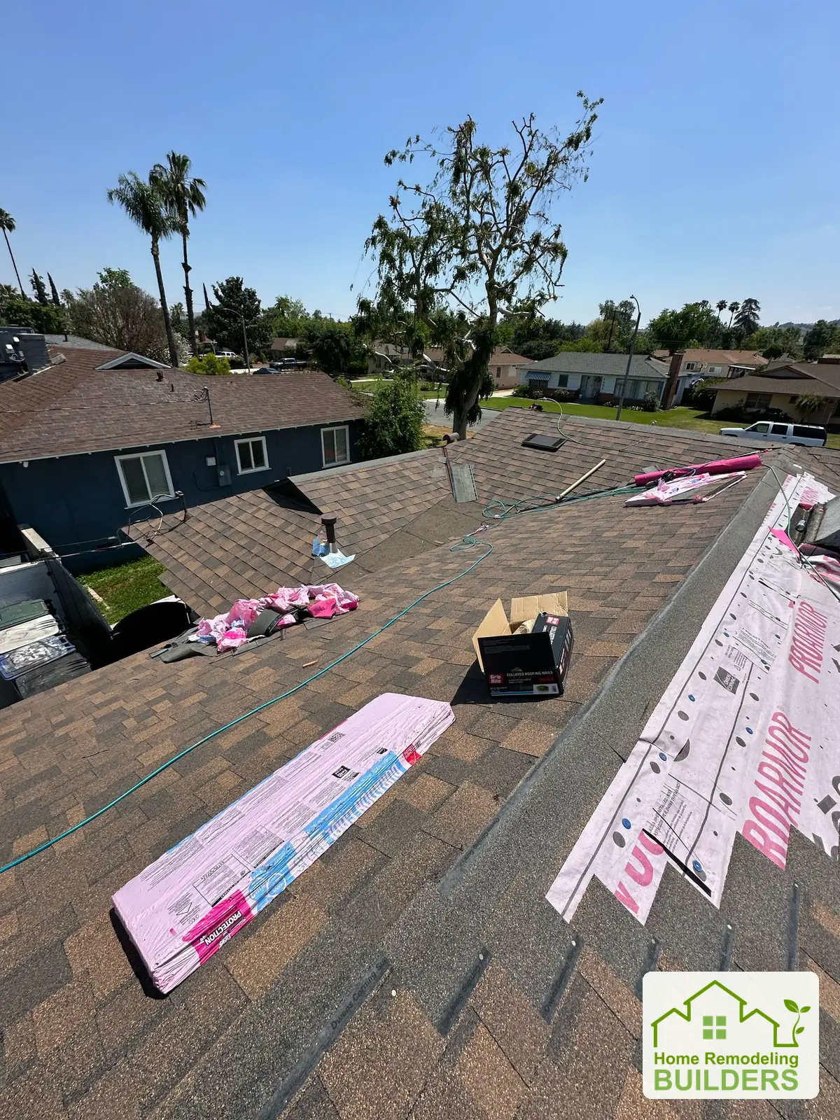 Shingle courses being installed below the staged roofing bundles. Riverside roofing project.