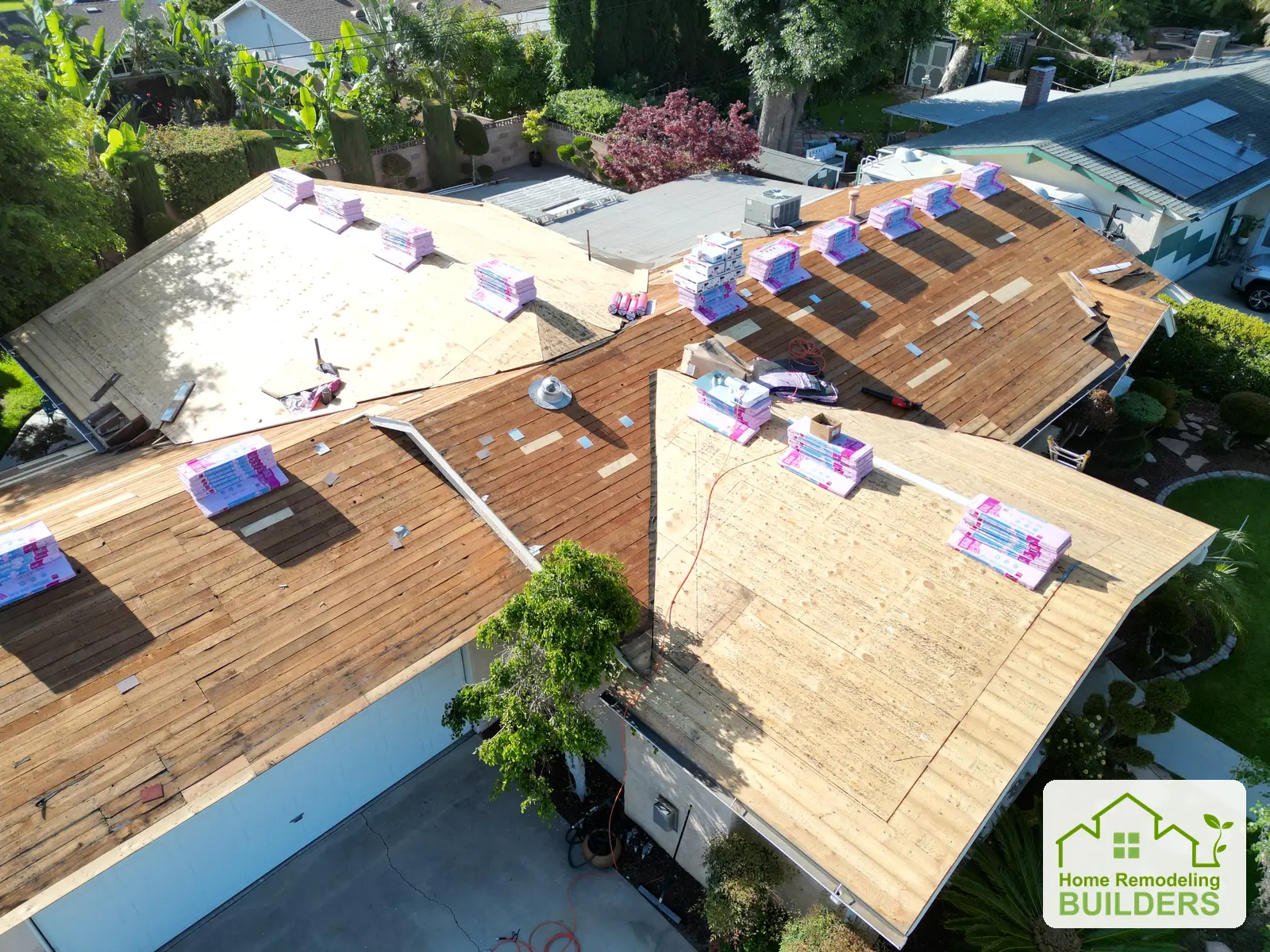 Roof preparation from the opposite side of the home, showing decking and material placement.