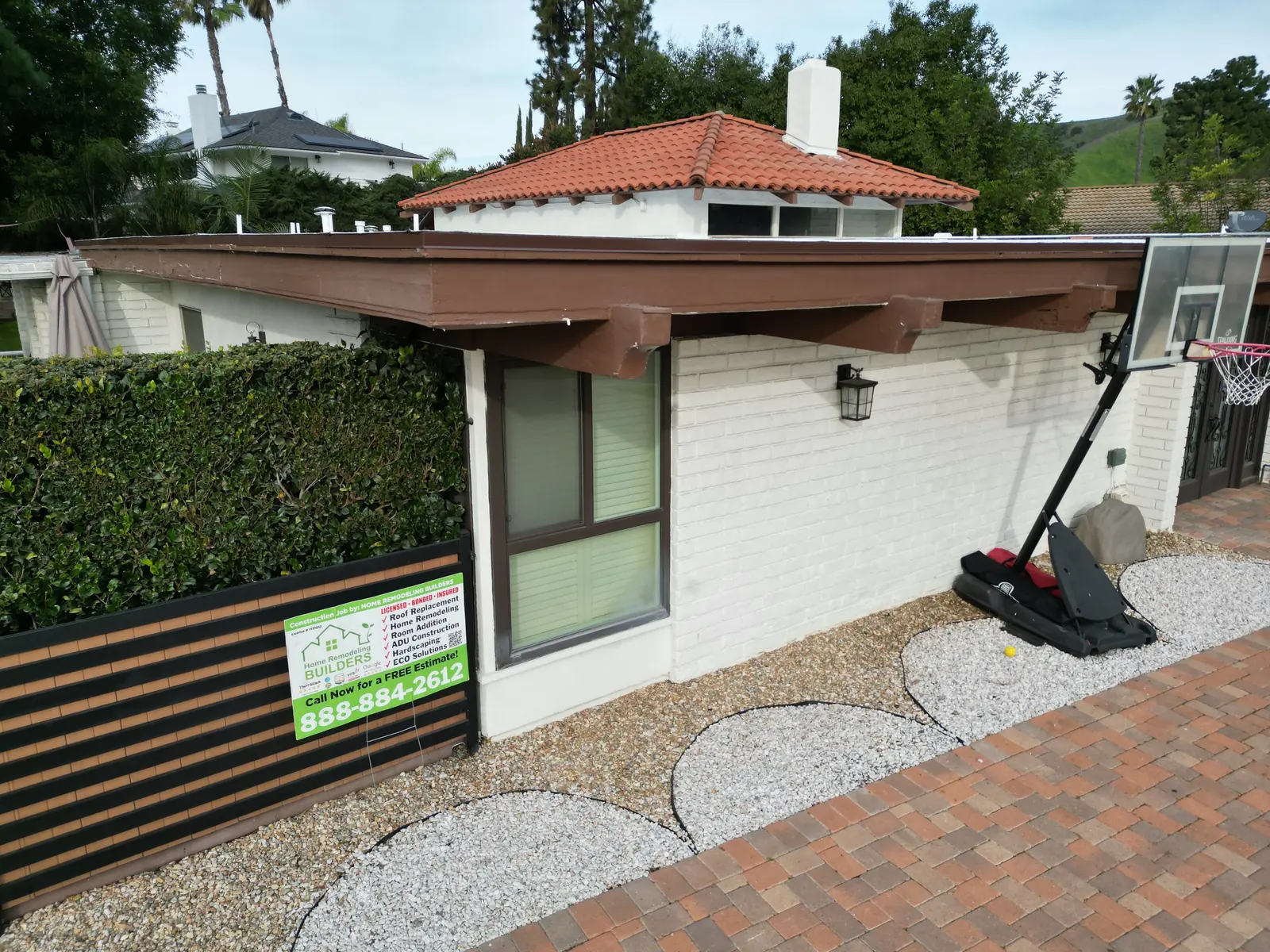 The finished roof edge and company sign at street level. Whittier Â· Flat roof roofing project.